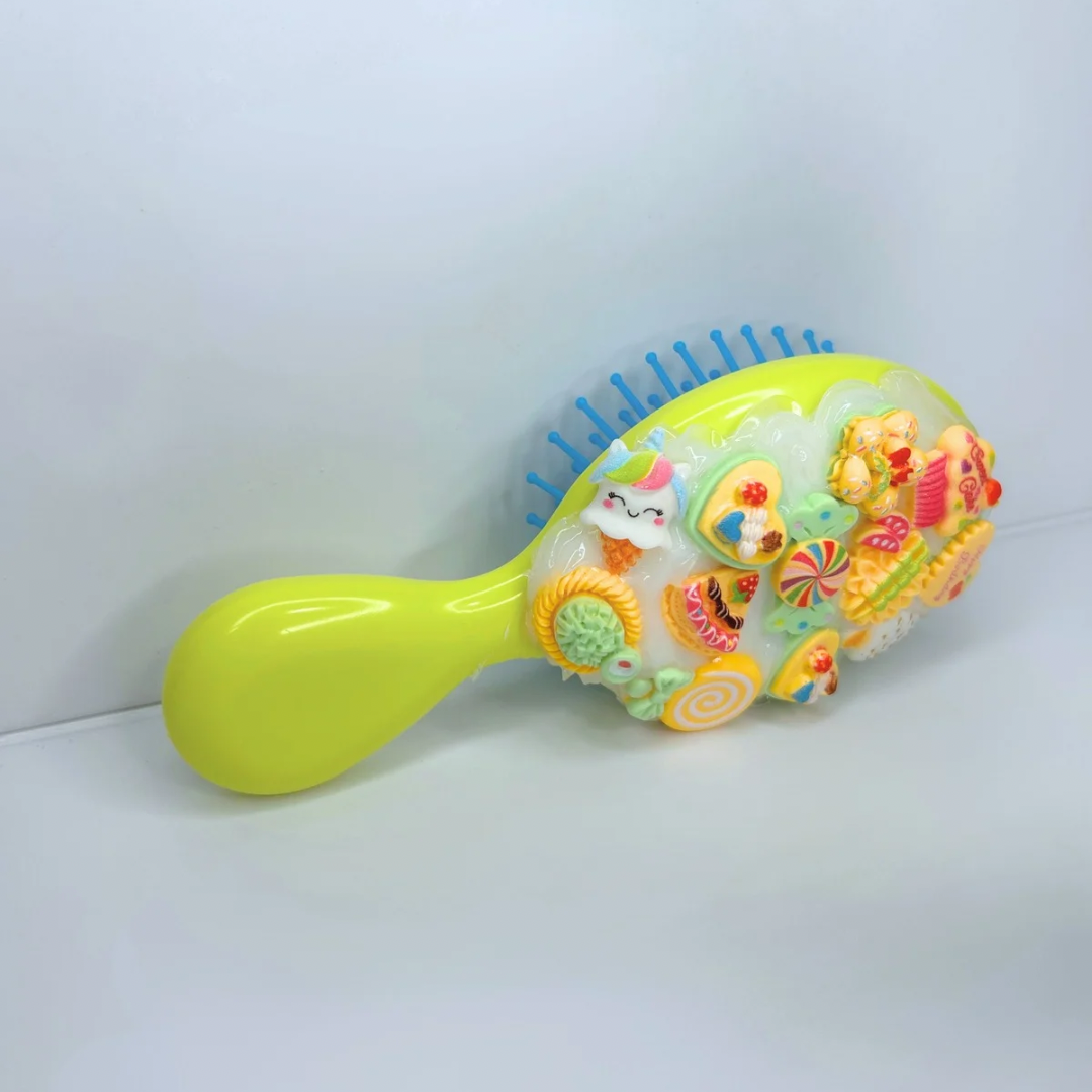 Top-down view of the yellow travel brush, highlighting charm layout and sleek, easy-to-grip shape