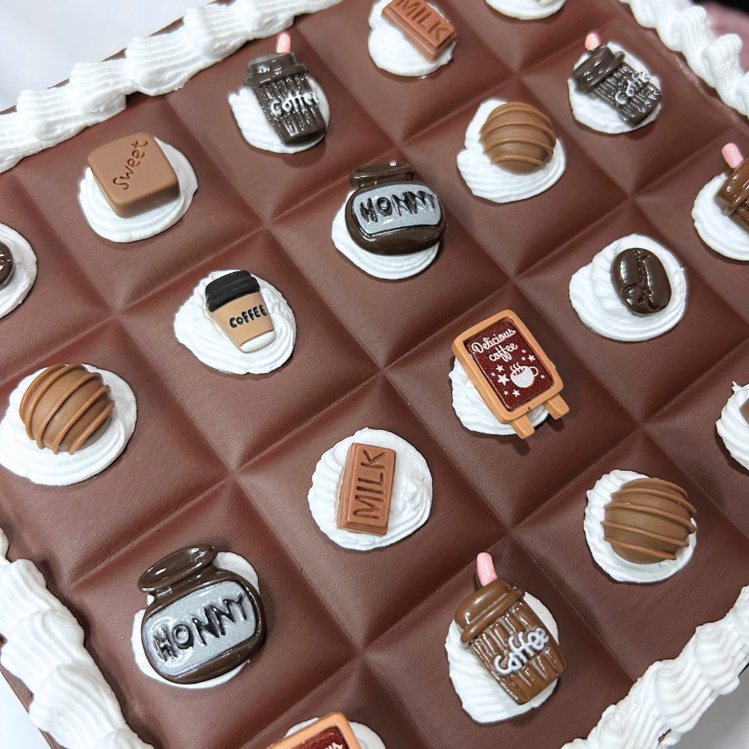 Chocolate-themed purse closeup with various chocolate decoration charms and frosting.