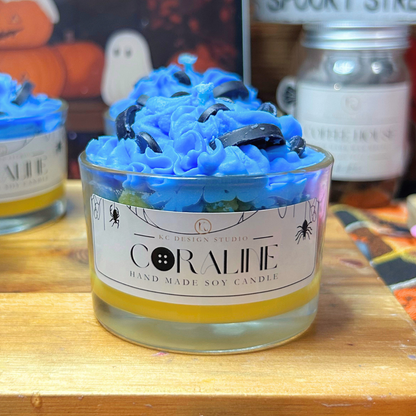 Halloween-themed jar candle with bright blue whipped wax tops and black button decorations, displayed on a wooden board with a Halloween-themed sign in the background.