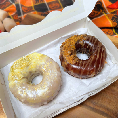 Two donut-shaped wax melts, Lemon Drop and Honey Crunch, displayed inside a small bakery box with the lid open.