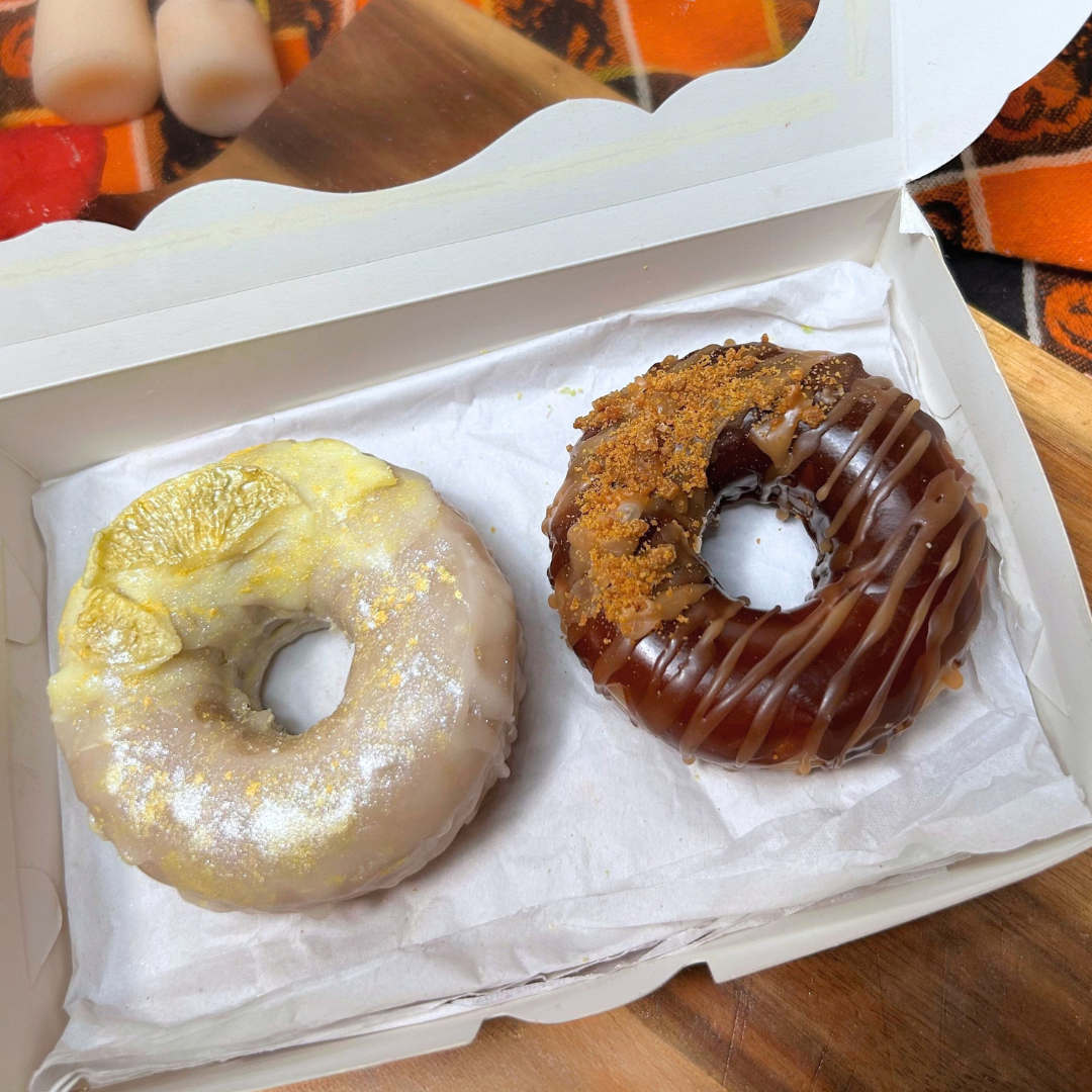 Open bakery box featuring two handmade donut wax melts with lemon icing, honey-colored drizzle, and bakery-inspired details.