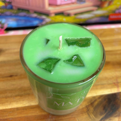Green matcha candle with a visible brand logo on a wooden surface