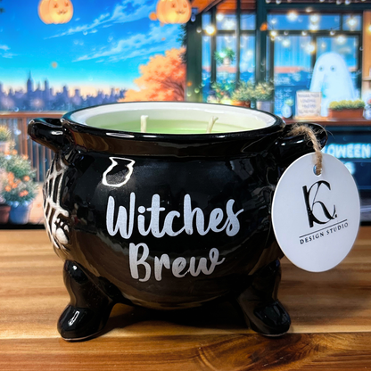 Black cauldron-shaped candle with "Witches Brew" text and a tag on a wooden surface.