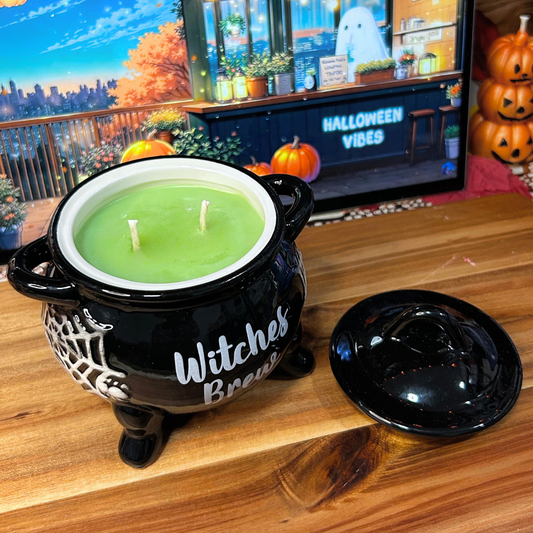Halloween-themed cauldron candle with "Witches Brew" text on a wooden surface, with a screen displaying Halloween Vibes in the background.
