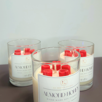Angled view of three 10oz Almond Honey & Pink Grapefruit candles, showcasing the soy wax, heart-shaped melts, and premium vessel design.