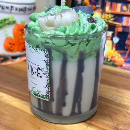 Side view of 10 oz Beetlejuice-inspired candle showing the black striped glass, white Cocoa Butter wax base, and green Birthday Cake whipped topping.
