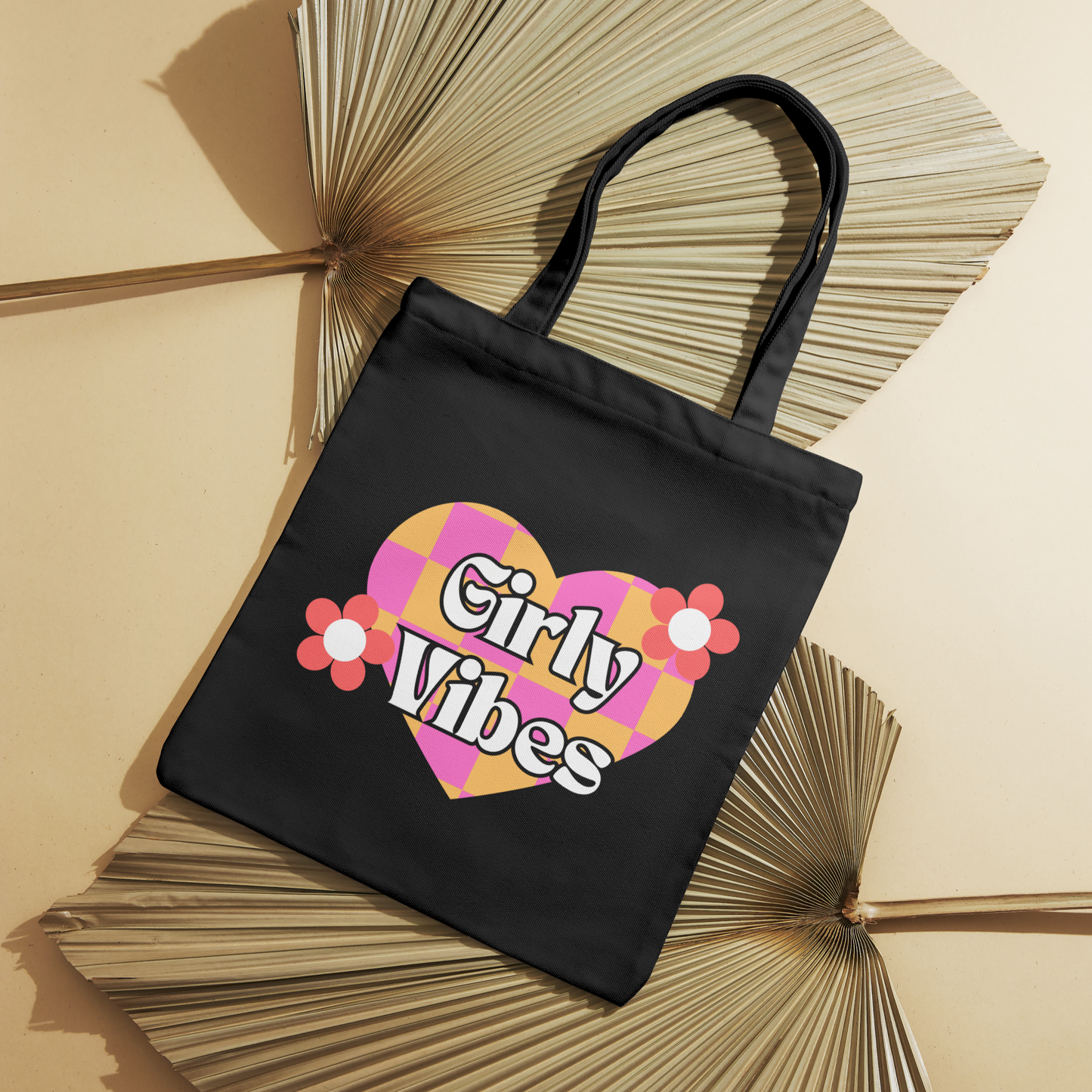 Black canvas tote bag with a multi-colored heart, pink flowers, and "Girly Vibes" text. Stylish and durable for daily use.