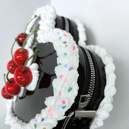 Close-up of the black heart-shaped purse highlighting the cherry cake design, with detailed frosting, sprinkles, and vibrant cherry accents.