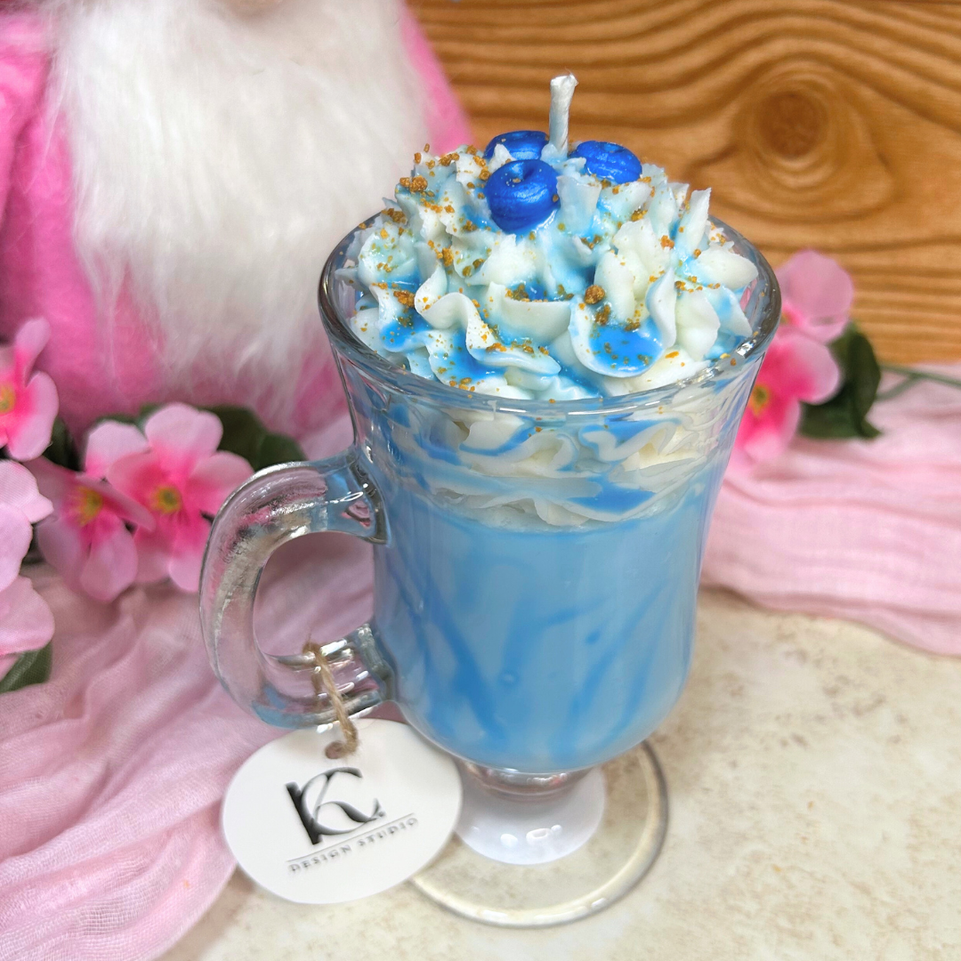 Blueberry Milkshake Candle styled on a pink background, showing the clear mug, whipped cream topping, and blueberry syrup drizzle
