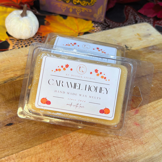 Front view of Caramel Honey Wax Melts packaging on a wooden surface with autumn decorations.