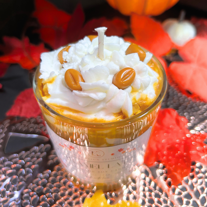 Candle in a glass jar with whipped cream and caramel candy on a decorative surface with pumpkins and leaves.
