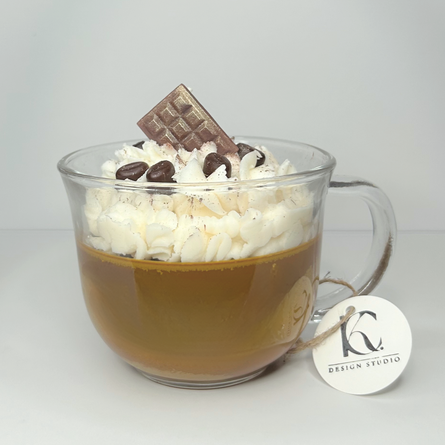 Front view of Chocolate Vanilla Latte Candle in an 18oz glass mug, showcasing layers of whipped cream, mini coffee beans, and a chocolate bar on top, with a rich blend of coffee house, vanilla buttercream, and salted caramel scents.