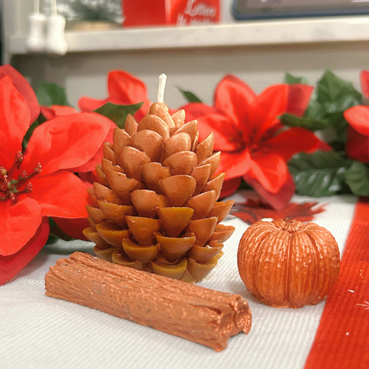 Front view of the Cinnamon Spice Set displaying a cinnamon stick wax melt, a mini pumpkin wax melt, and a decorative pine cone candle in earthy brown shades.