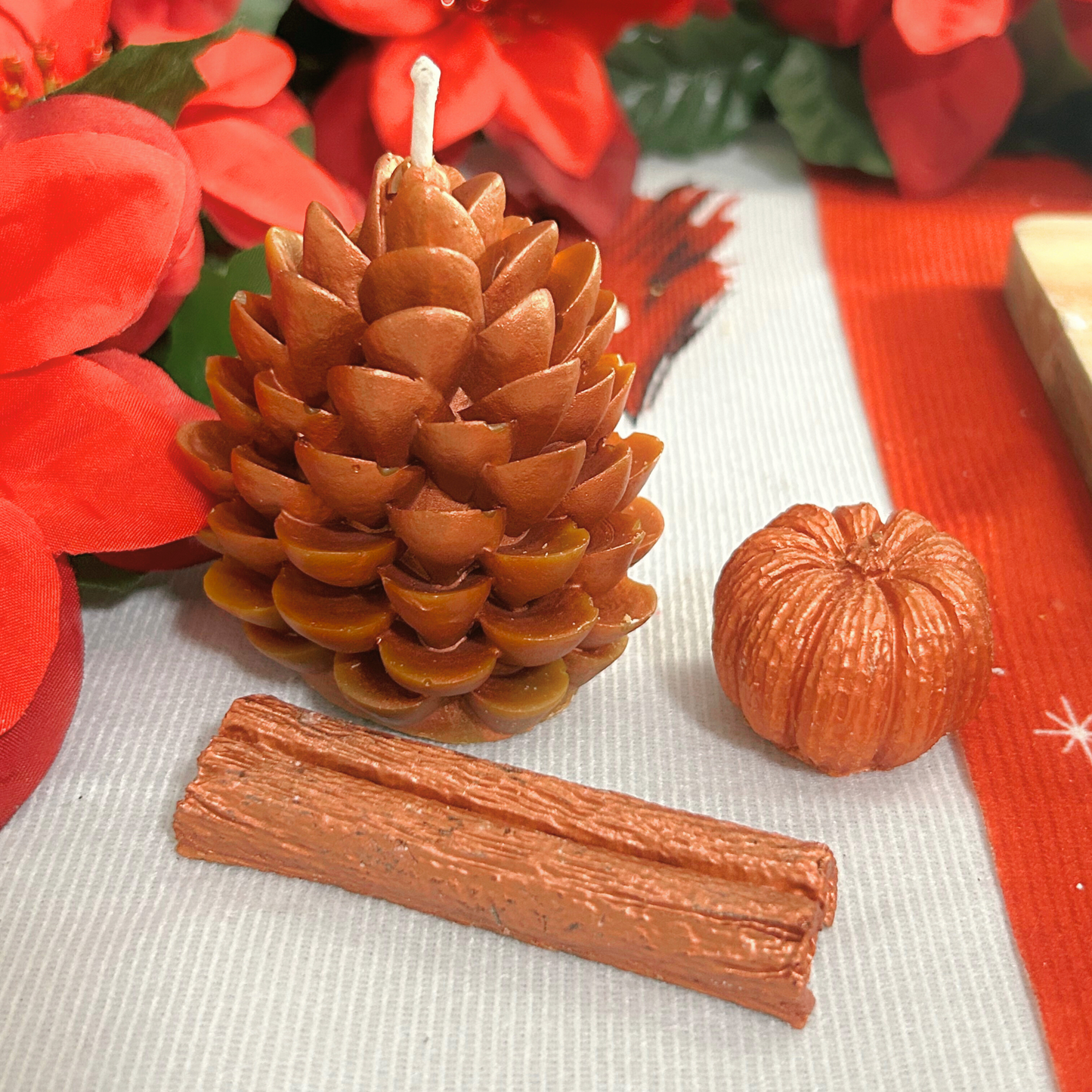 Side top view of the Cinnamon Spice Set featuring a cinnamon stick wax melt, a mini pumpkin wax melt, and a decorative pine cone candle in warm brown tones.