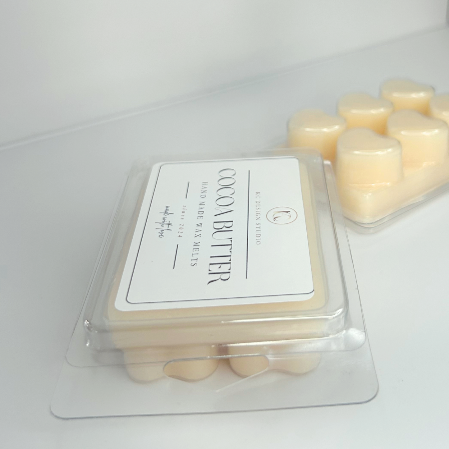 Angled close view of Cocoa Butter Cashmere wax melt featuring label and heart-shaped plastic packaging