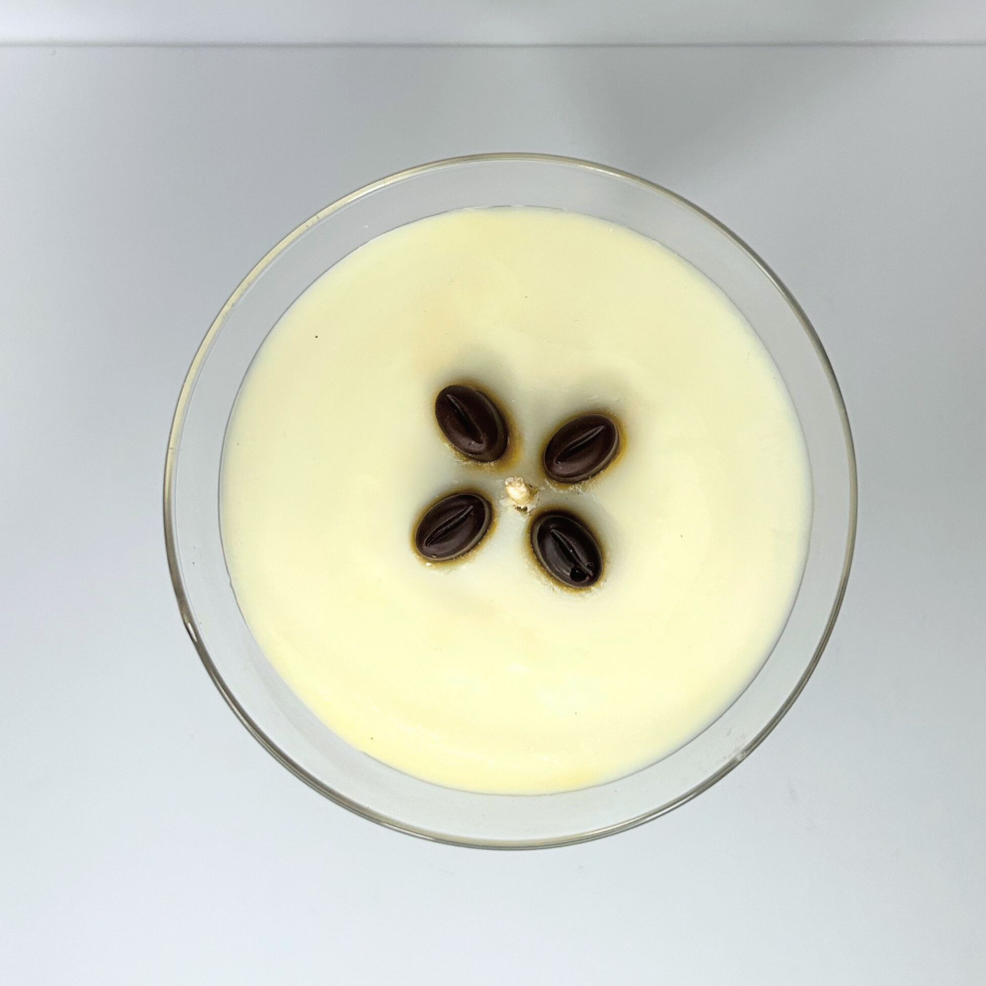 Top view of a beautifully layered martini candle showing the creamy top layer of French vanilla scented, adorned with four coffee beans.