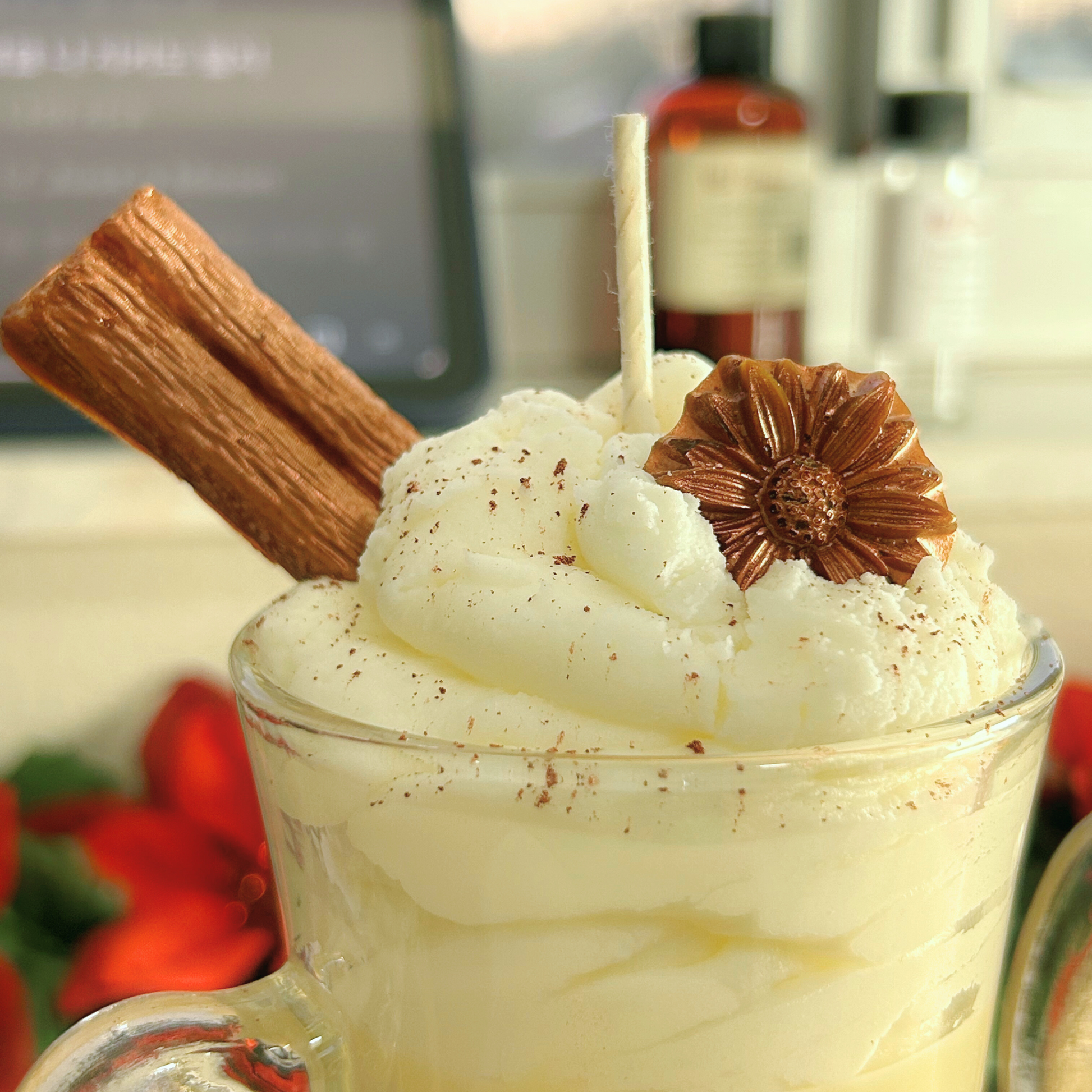 Close-up of a Coquito Christmas candle detailing its brown sparkly powder, cinnamon stick, and anise flower topping in an 8oz Irish cup.