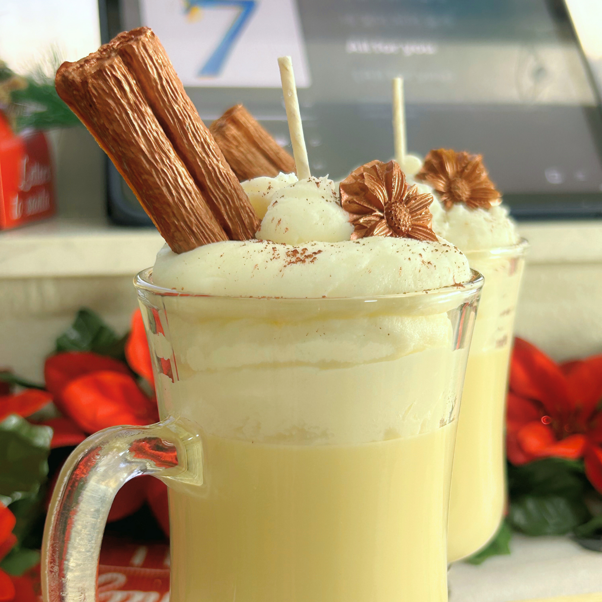 Side view of two Coquito Christmas candles highlighting the cream-colored base, white whipped layer, and decorative toppings in glass Irish cups.