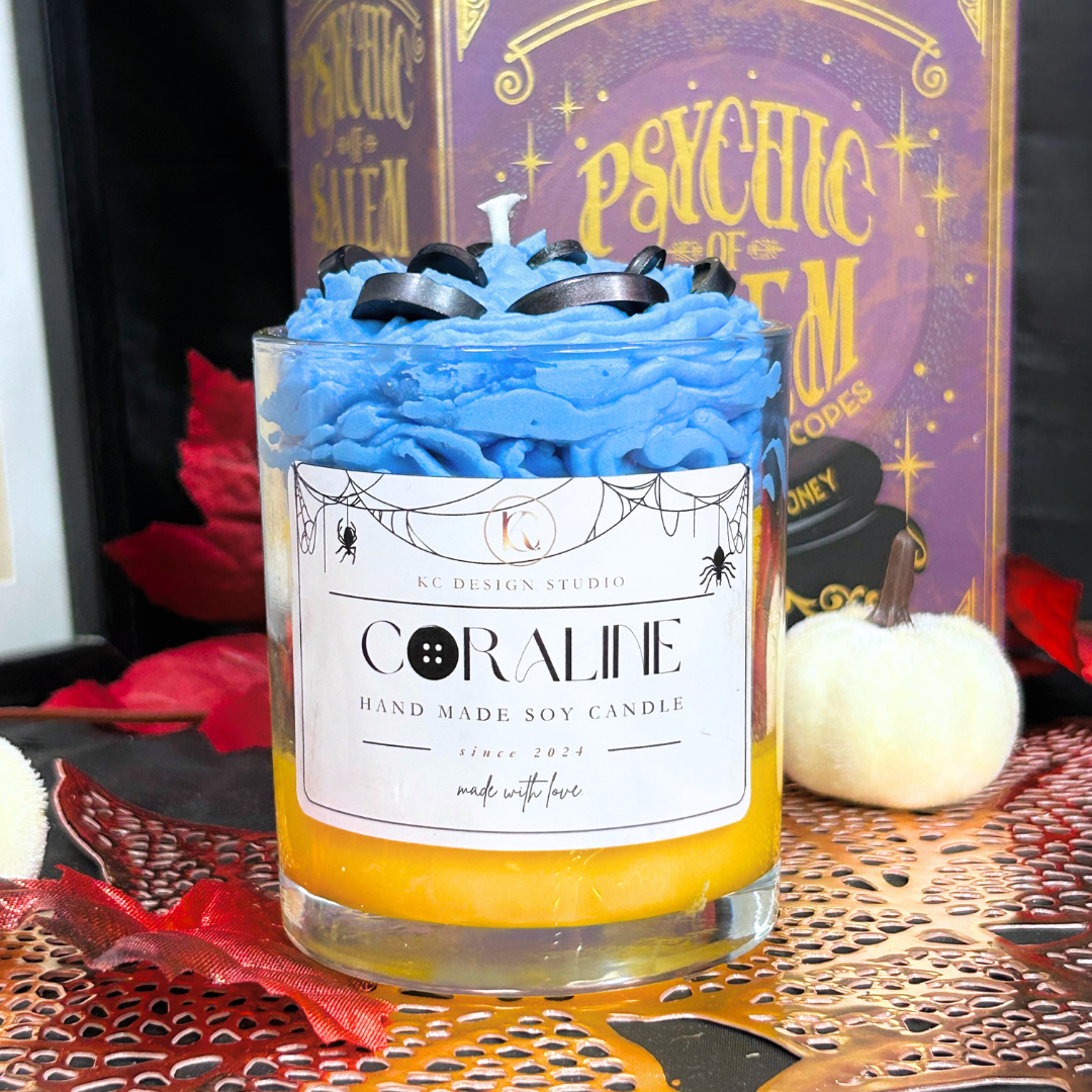 Front view of Coraline Halloween Candle with yellow layers, black button details, and blue whipped cream top.