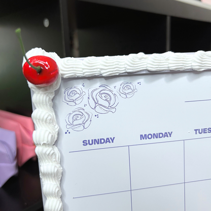 Calendar with a cherry on top of white frosting frame.