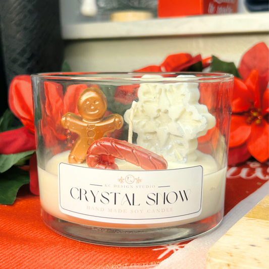 Front view of Crystal Snow candle with snowy white wax, snowflake, gingerbread man, and candy cane in a 16oz glass jar.