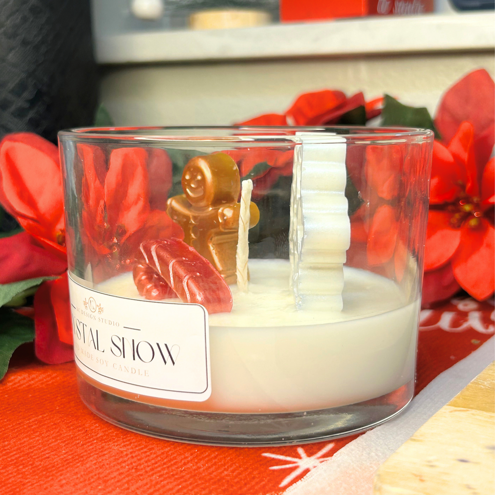 Side view of Crystal Snow candle showing snowflake, gingerbread man, and candy cane details on a snowy wax base.