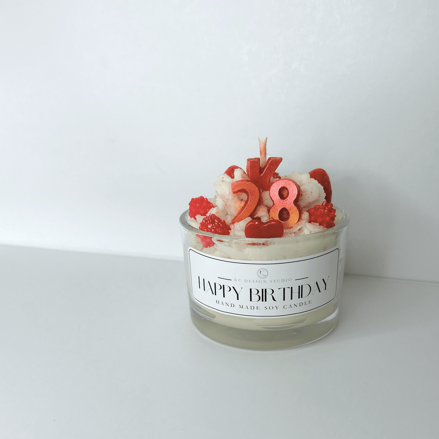 Front view of Custom 4oz Birthday Candle, showcasing its personalized toppings, initial, and age, with a clear view of the eco-friendly design.