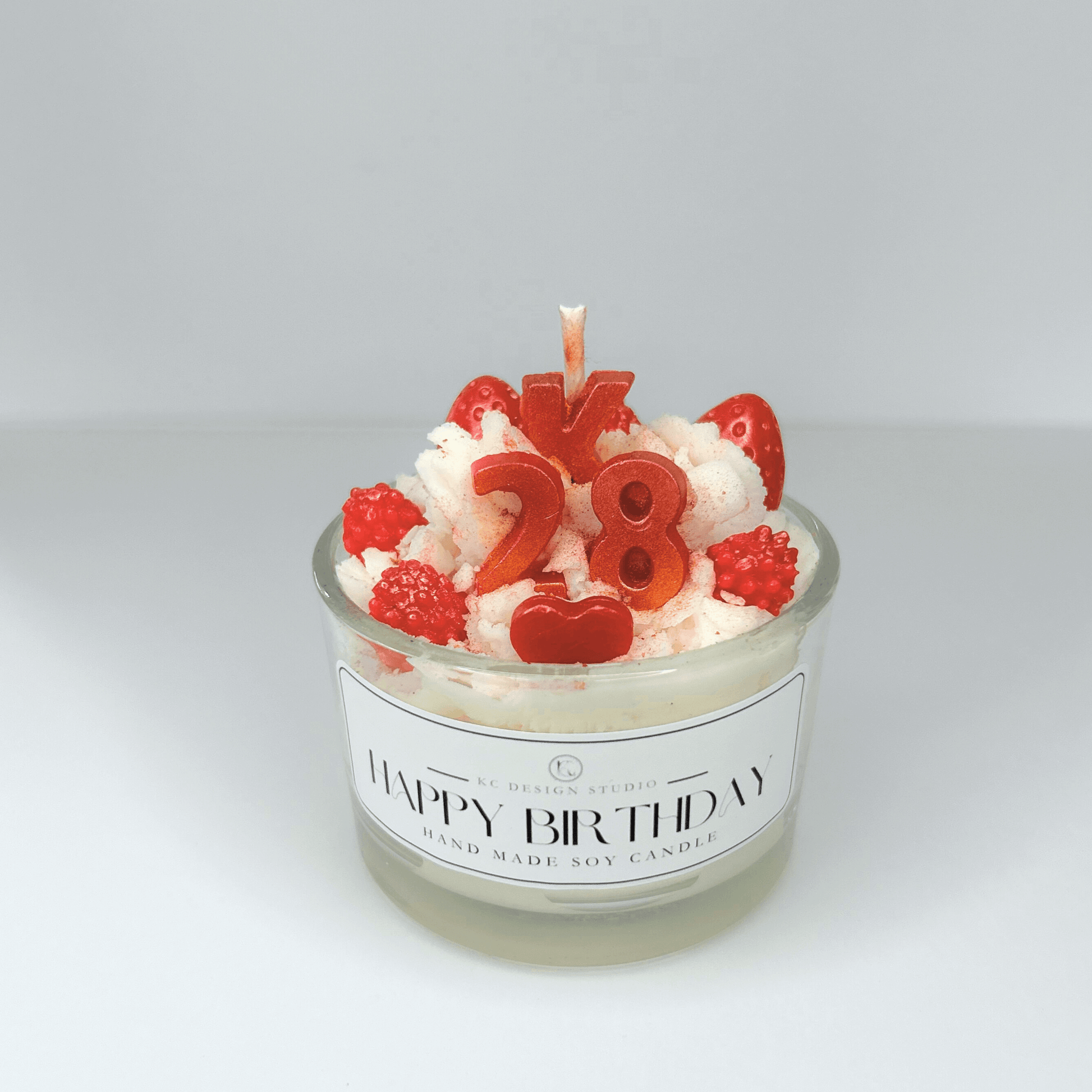 Close-up of Custom 4oz Birthday Candle with personalized initial "K" and age "28" in decorative toppings.