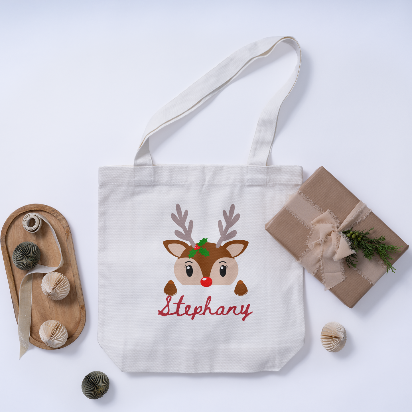 Top view of a custom Christmas white tote bag with a reindeer design on the initial and an option for a personalized name for a unique holiday gift.
