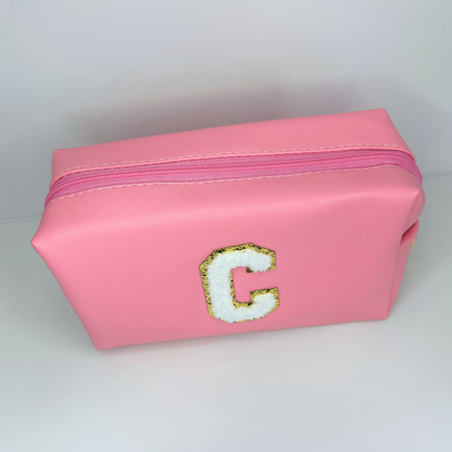Pink initial letter cosmetic pouch – top view focusing on zipper and stitching.