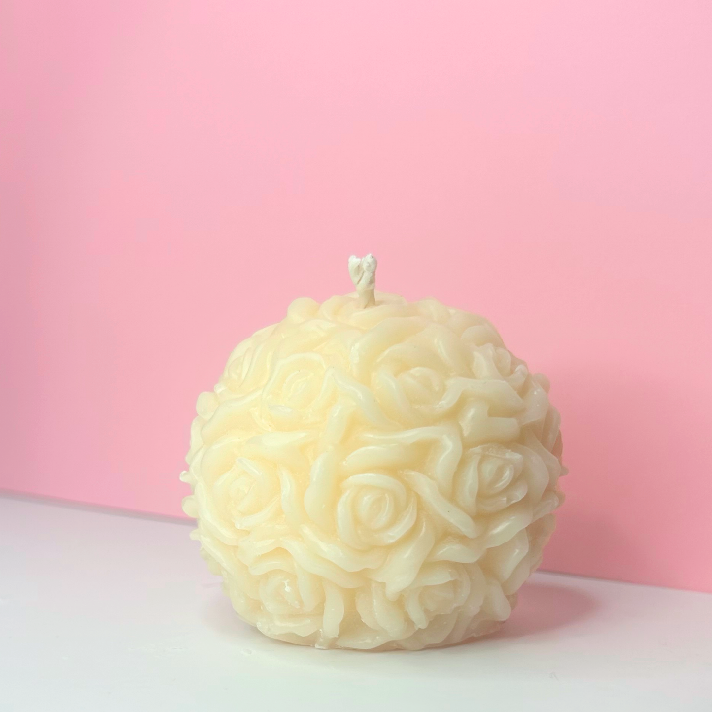 Front view of the Decorative Blossom Breeze Candle against a pink background, showcasing its floral design and all-natural soy wax.