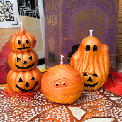 Halloween-themed candles including a stack of pumpkin-shaped candles, a mummy-shaped candle, and a ghost-shaped candle.
