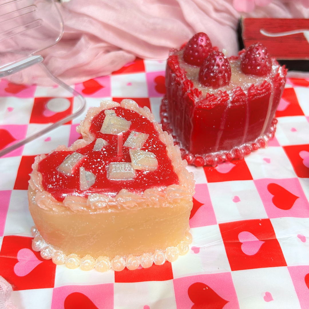 Two heart-shaped sweet dessert candles on a checkered tablecloth with heart patterns.