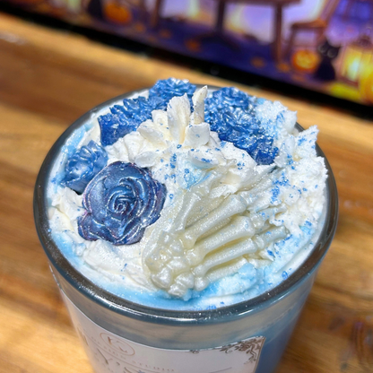 Close-up of Emily’s Veil candle details showing the blue roses, blue butterfly, white bone hand, and textured whipped wax topping.