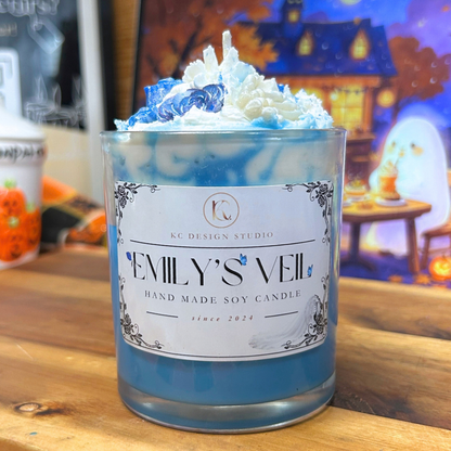 Emily’s Veil 10 oz soy candle with a light blue wax base, white whipped wax topping, two blue roses, a blue butterfly, and a white bone hand, inspired by Corpse Bride.