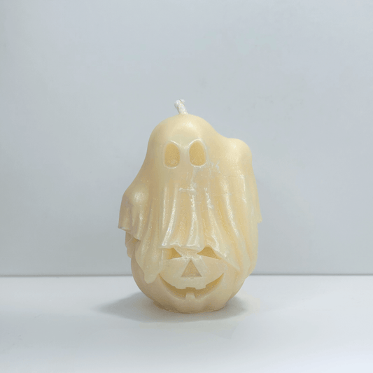 Front view of decorative ghost candle with cotton candy scent, featuring a ghost sitting on top of a pumpkin.