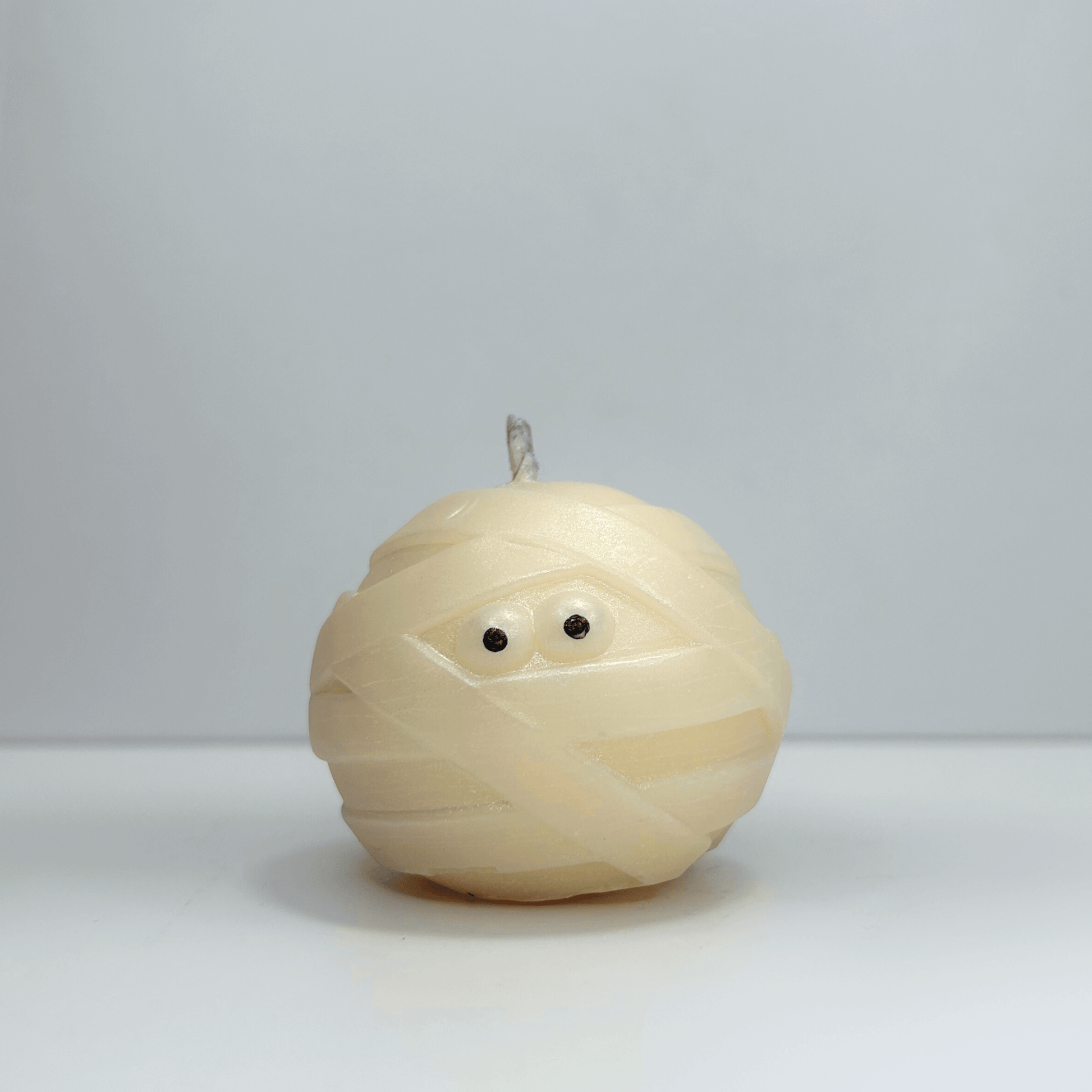 Front view of decorative mummy candle with visible eyes, perfect for Halloween decor.