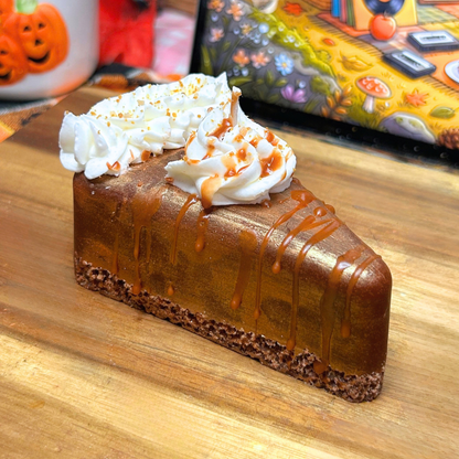 Side view of the Golden Pumpkin Pie candle showing the layered pie design, crumb base, golden filling, whipped cream, and syrup topping.