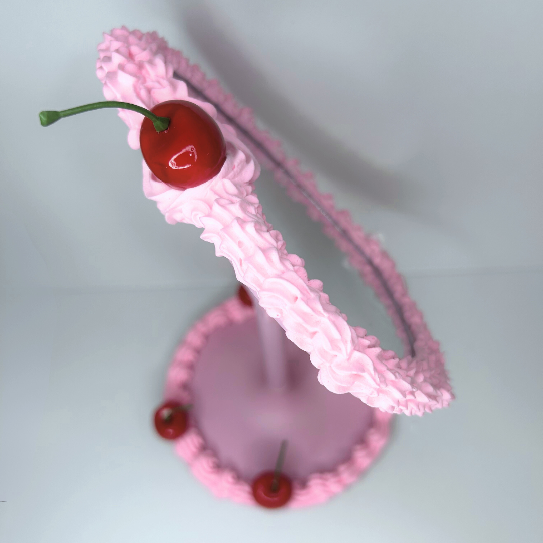 Close-up of cherry frosting detail and LED light on heart-shaped vanity mirror.