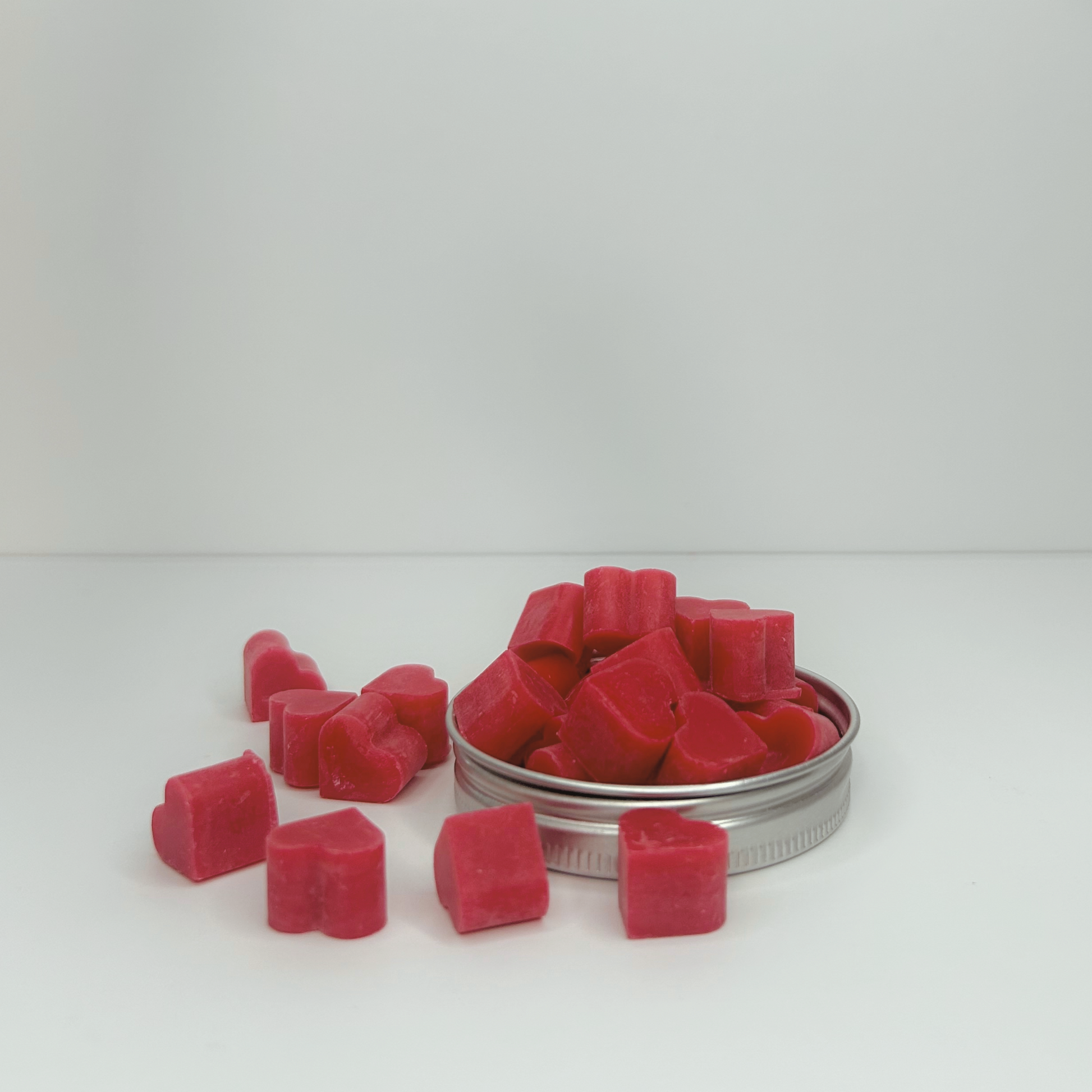 Side view of Heart of Citrus Wax Melts in a lid, highlighting the heart shapes and colorful red wax.