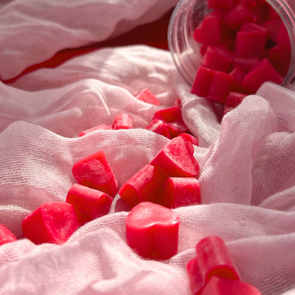 Close up of Heart of Citrus wax melts spilled out of the jar, highlighting the mini heart-shaped design and vibrant pink grapefruit scent release.