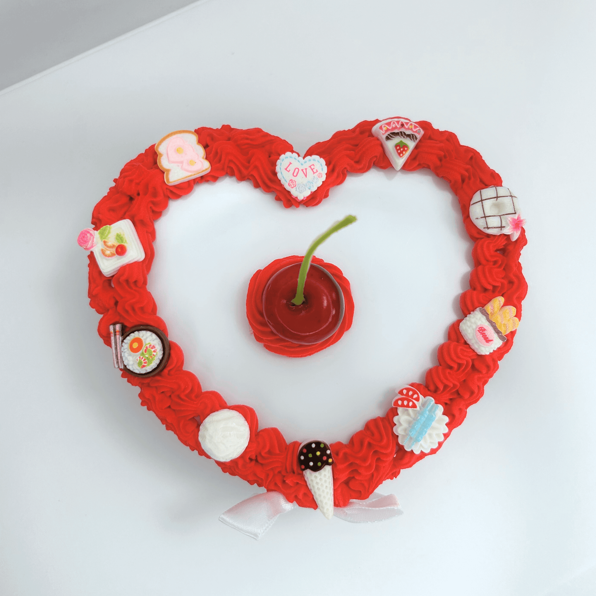 Top view of the heart-shaped red and white jewelry box adorned with cute foodie charms and a cherry on top, featuring a delicate white bow.