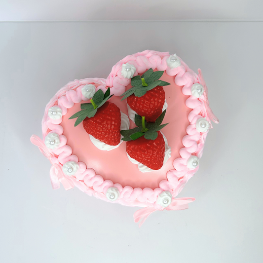 Heart-shaped vintage jewelry box in pink and white with three strawberries, pearls, and mini pink bows on top.