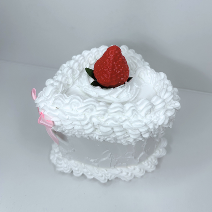 Side view of heart-shaped cake storage box with white frosting and pink bow.