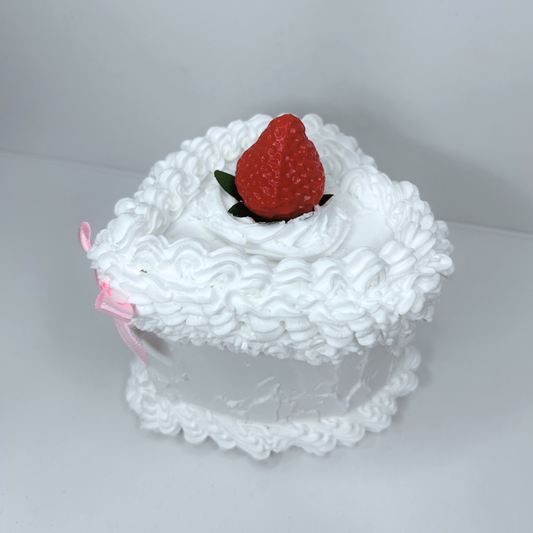 Side view of heart-shaped cake storage box with white frosting and pink bow.