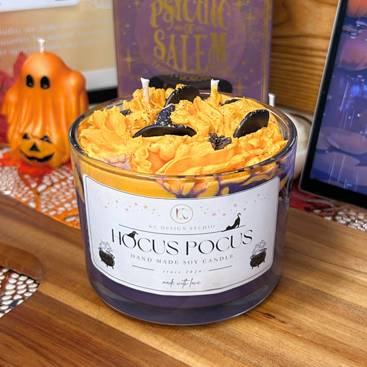Hocus Pocus candle with a Salem book and ghost candle in the background on a wooden surface.