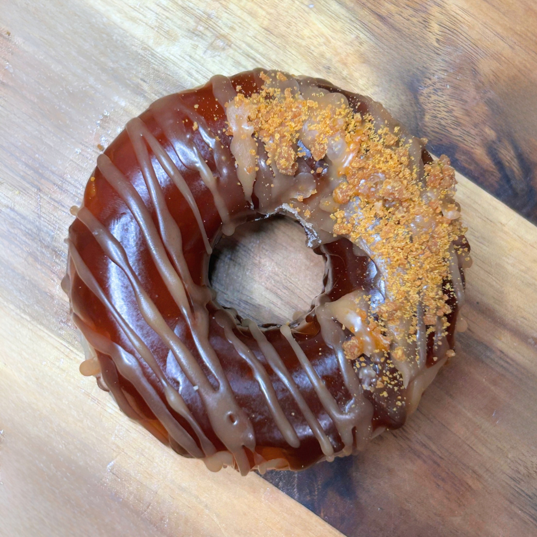 Single Honey Crunch donut wax melt with dark brown icing, light brown syrup lines, and crumb details.