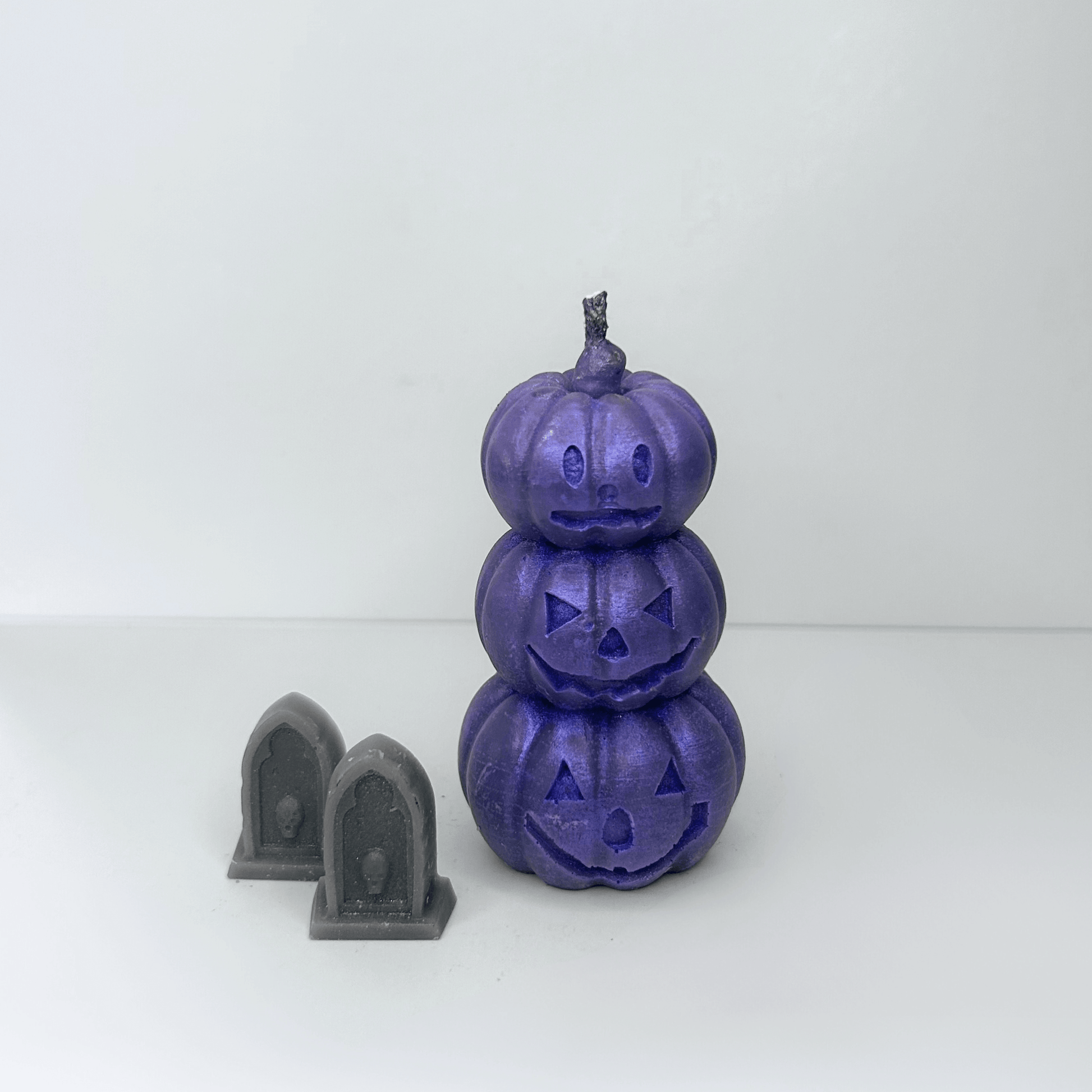 Front view of the purple Jack-O-Lantern Candle showcasing three stacked pumpkins with whimsical Halloween faces, adding a sparkly touch to Halloween celebrations.