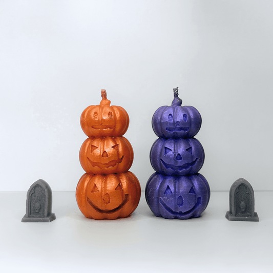 Front view of both the orange and purple Jack-O-Lantern Candles, showcasing three stacked pumpkins with playful Halloween faces, perfect for festive decor.