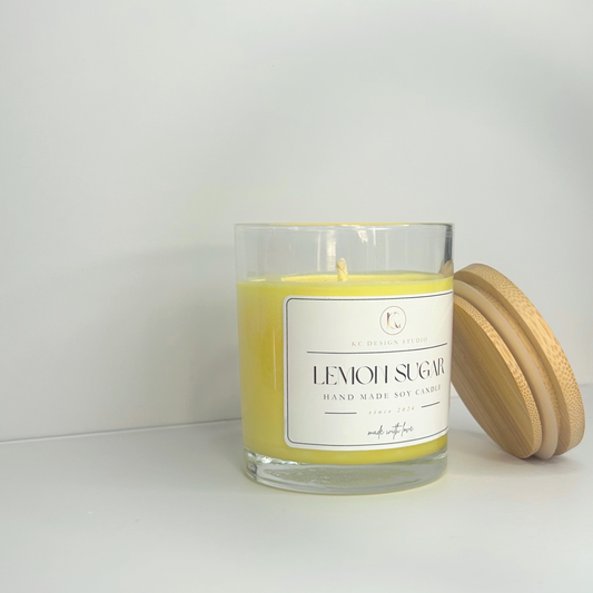 Side view of the 10oz Lemon Sugar Candle with lid resting on the side, showcasing its bright yellow color and elegant design.